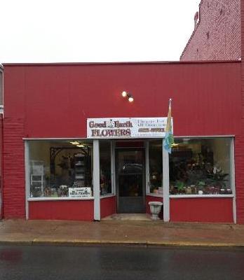 A small florist shop with a red storefront and a sign above the door that reads 