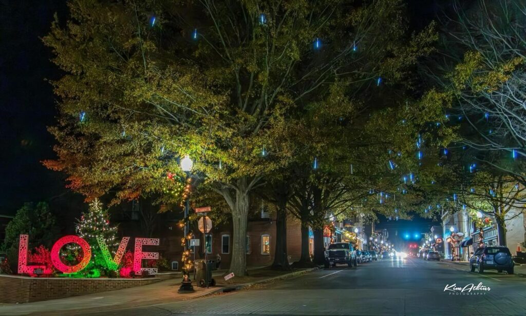 A nighttime street scene adorned with festive lights sets the perfect ambiance for holiday shopping. 