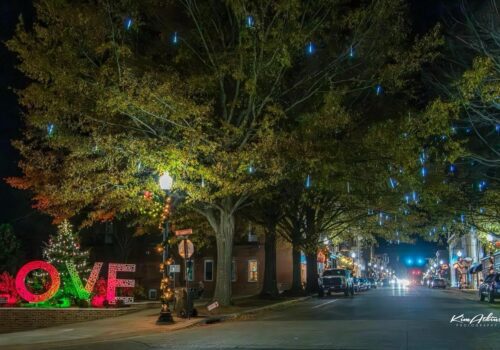 A nighttime street scene adorned with festive lights sets the perfect ambiance for holiday shopping. 