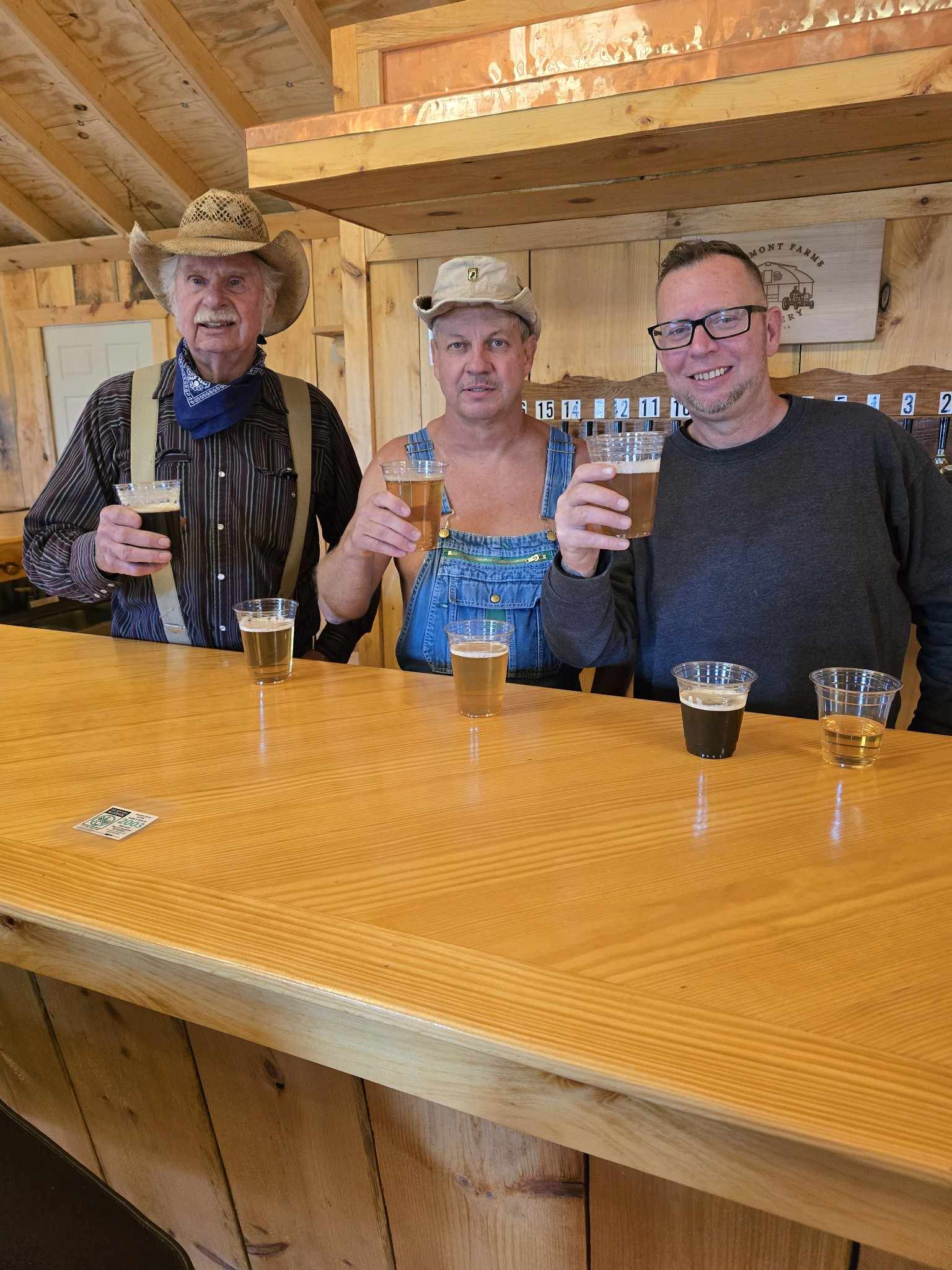 three men at a bar holding a beer