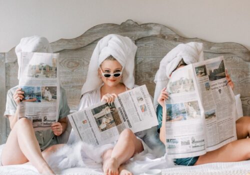 thee girls on a bed reading a newspaper