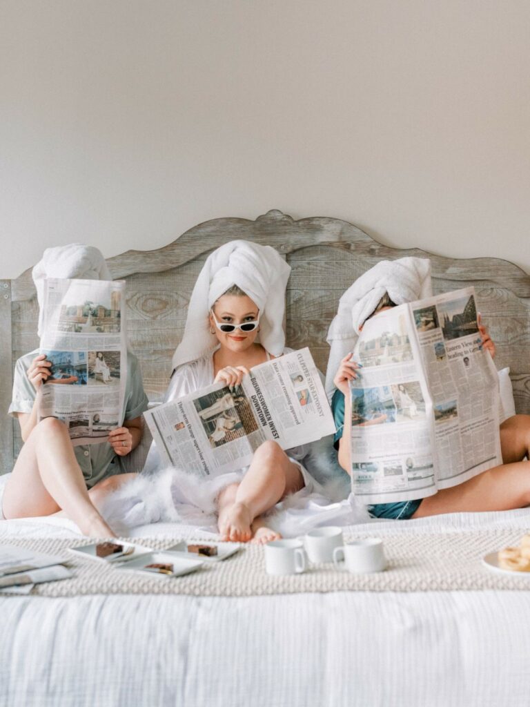 thee girls on a bed reading a newspaper