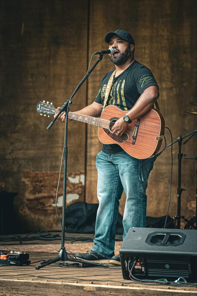 man singing and playing guitar on stage