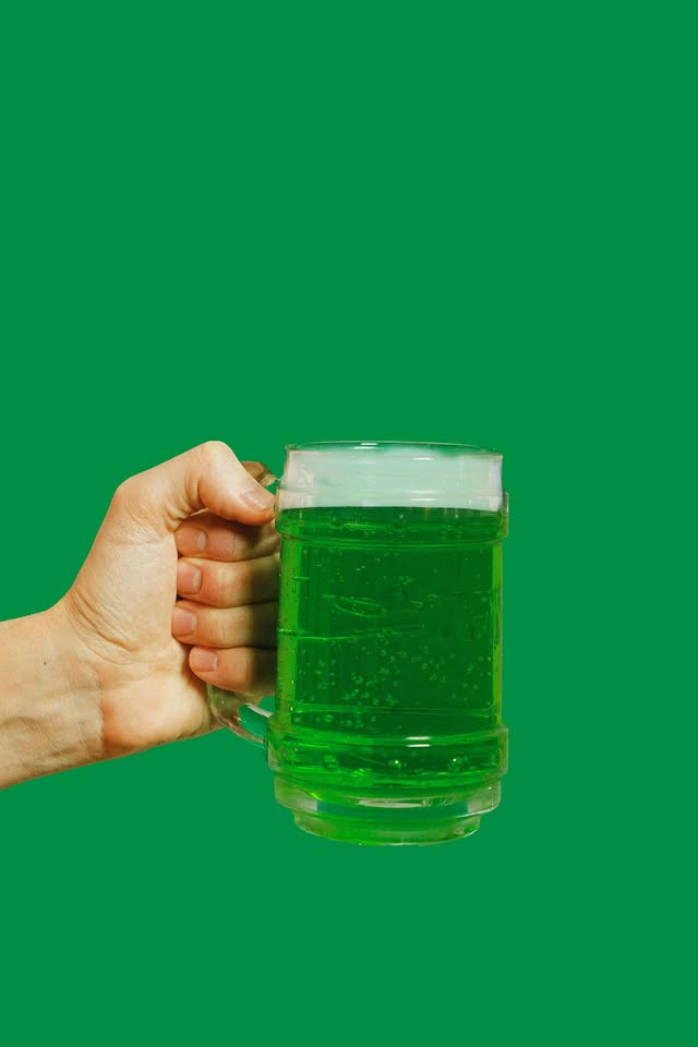 hand holding a beer mug with green beer