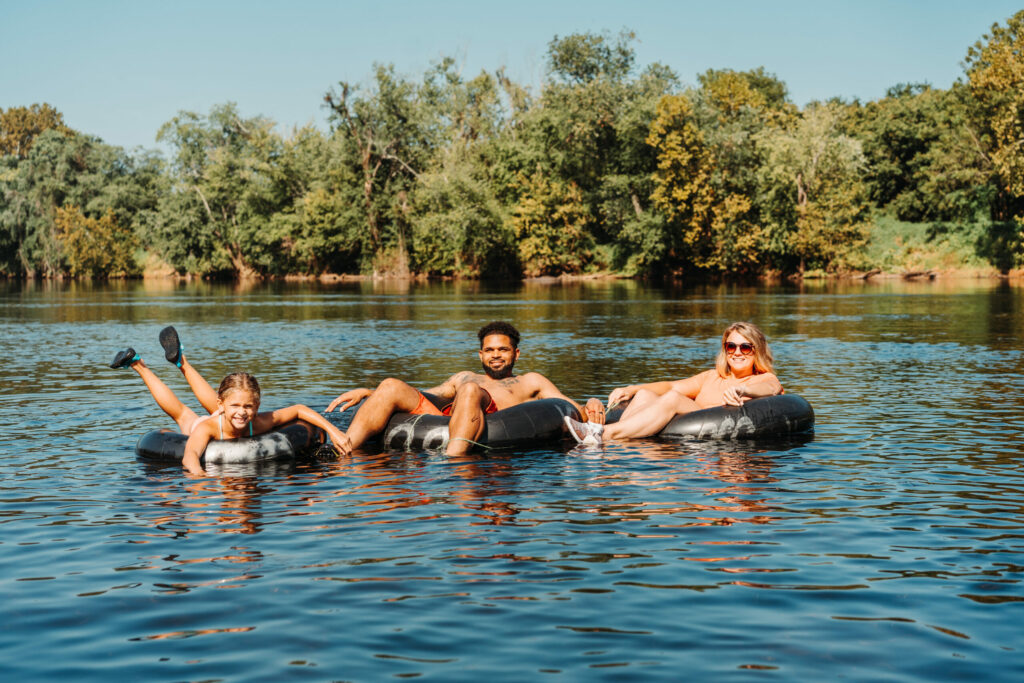 three people in a tube floating on a river