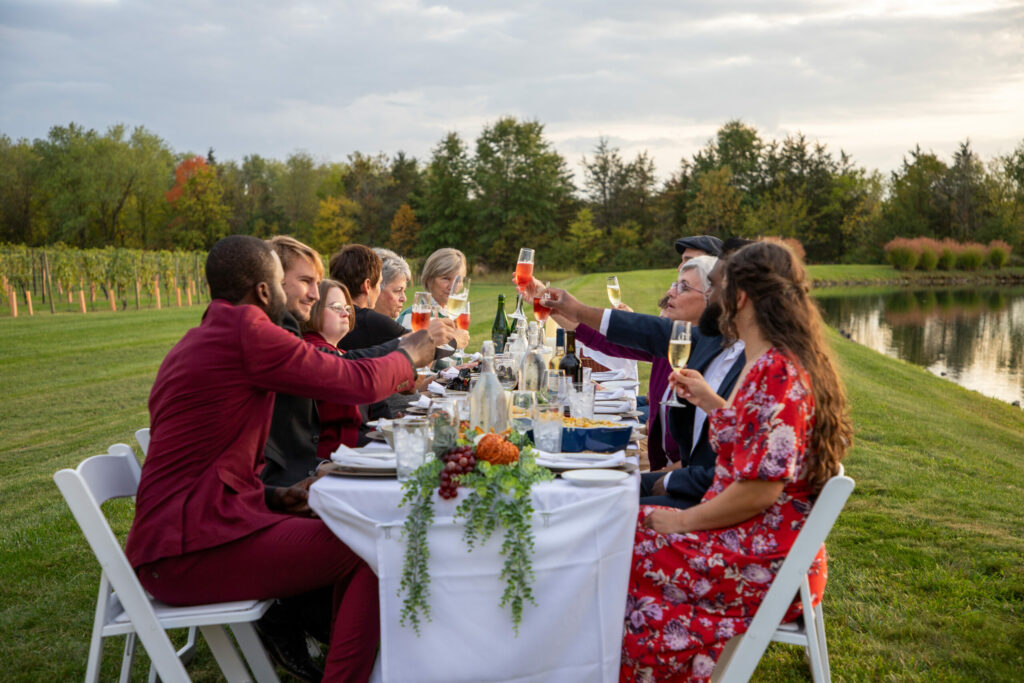group of people dining at a table outdoors, in a field