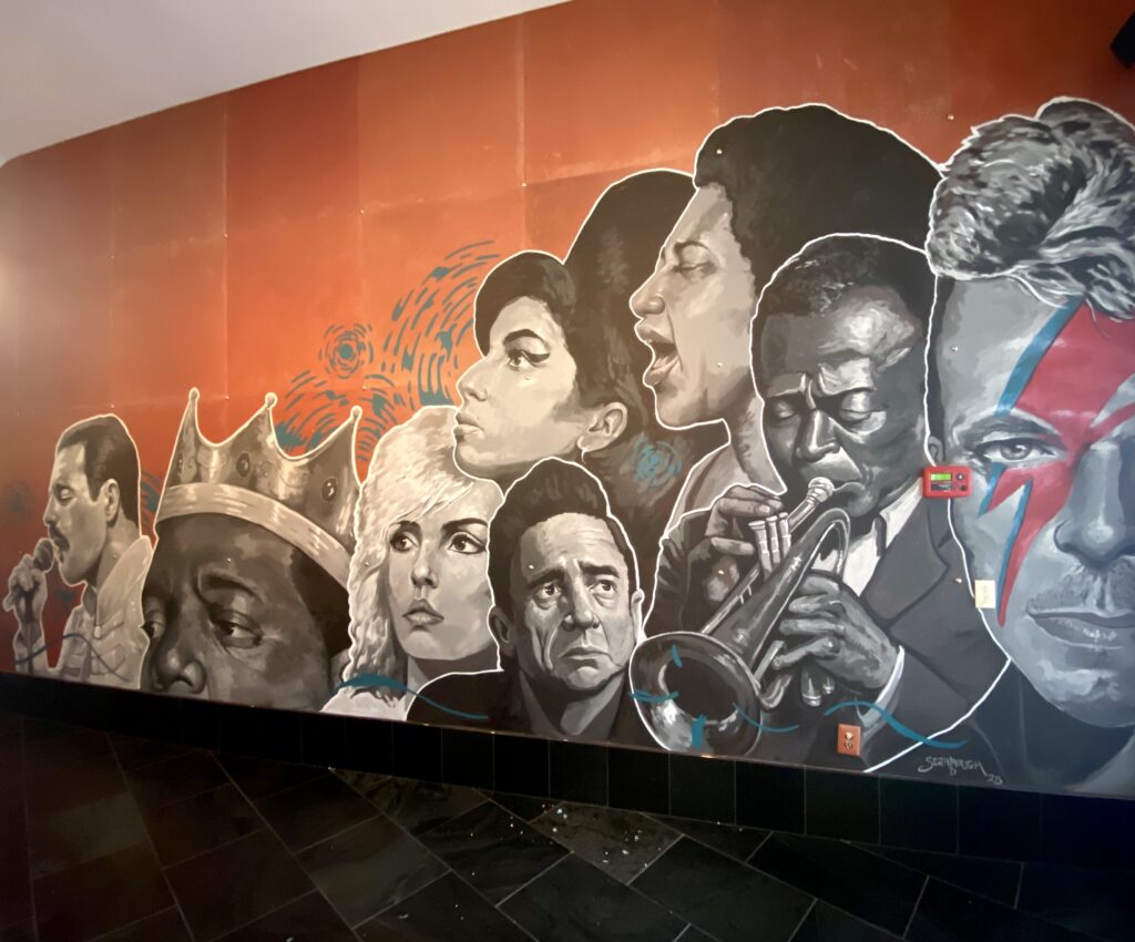mural of musical icons including Amy Winehouse, Johnny Cash, Dolly Parton and others